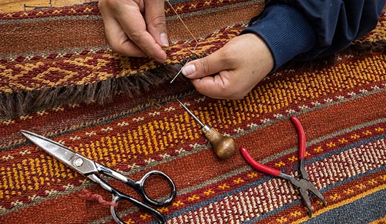 woman hand rug repair needle closeup string