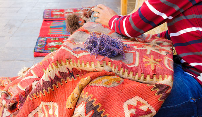 woman repairing red rug in Coldspring
